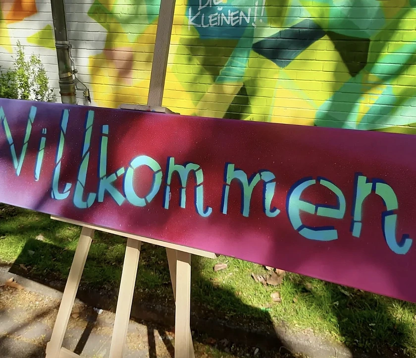 Die Kinder haben Willkommensschilder auf verschiedenen Sprachen gesprüht.